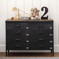 a black dresser with numbers on it and a lamp in the corner next to it