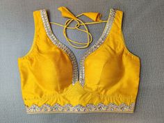 Shop stunning yellow sleeveless sari blouse online in USA with silver embroidery lace. Elevate your Indian ethnic saree looks with beautiful readymade sari blouse, embroidered saree blouses, Banarasi saree blouse, designer sari blouses, sleeveless saree blouses from Pure Elegance Indian fashion store in USA.-front Elegant Yellow Blouse With Mirror Work, Yellow Sleeveless Choli With Pallu, Yellow Tops For Diwali Wedding, Yellow Tops For Wedding And Diwali, Yellow Dori Work Party Blouse, Festive Yellow V-neck Top, Yellow Party Tops For Diwali, Yellow Fitted Sleeveless Blouse Piece, Sleeveless Gold Choli With Mirror Work