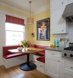 a kitchen with a table and two red chairs next to a stove top oven in front of a painting on the wall