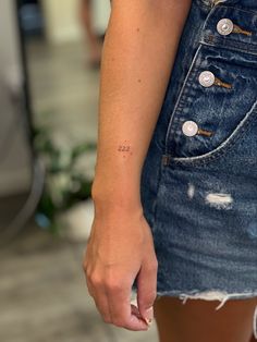 a woman with a small tattoo on her left arm holding onto a piece of denim