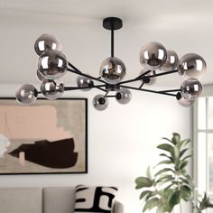 a modern chandelier hangs from the ceiling in a living room