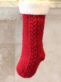 a red knitted christmas stocking hanging from a window sill with white trim