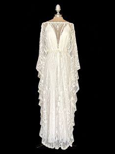 a white dress with sheer lace on the neck and sleeves, sitting on a mannequin