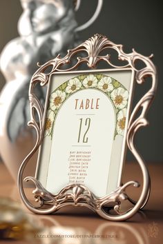 The pin shows a table numbers sign for weddings inspired by the artist Alphonse Mucha. White Lilies are draped around a highly ornamental frame surrounding the table number and the list of guests to be seated. The colors are white, green and gold/yellow. The table sign is editable and sold by Zazzle. The Design is by DIYPaperBoutique. Boho Art Deco Wedding, Wedding Art Nouveau, Vintage Nouveau Wedding, Art Nouveau Wedding Theme, Art Nouveau Wedding Decorations, Art Deco Wedding Centerpieces, Victorian Flourishes, Wedding Art Deco