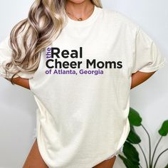 These super cute Comfort Colors® Real Cheer Moms shirts are a great gift for a cheer mom or even a team of cheer moms! It makes an entertaining group shirt while representing your local area! Customize your shirt with the shirt color, location (city and/or state), and the font colors. Perfect for wearing to cheer competitions, practices or games, these shirts come in neutral colors, but can be printed on virtually any color. For special color requests, please send me a message so I can get you a Custom Mom Cheer Shirts For Scorch, Cheer Coach Competition Shirts, Cheerleading Tshirts Designs Ideas, Cheer Team Mom Gift Ideas, White Soft-washed Fan Apparel Top, White Tops With Funny Text For Fans, Family Matching Cotton Tops For Game Day, White Soft-washed Tops For Game Day, Cotton Top With Funny Text For Game Day