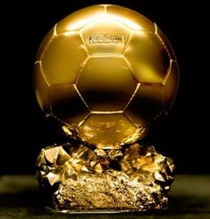 a golden soccer ball sitting on top of a crystal block with gold foil around it