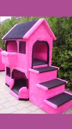 a pink and black house with steps leading up to the top floor in front of some bushes