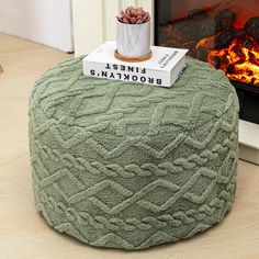 a green pouffle sitting on top of a wooden floor next to a fire place