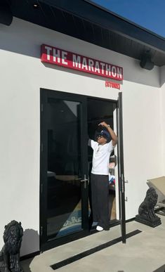 a young boy standing in the doorway of a building with his hand up to the door