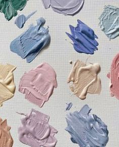 several different shades of paint sitting on top of a white surface with one being blue and the other is pink