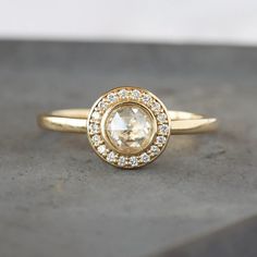 a yellow gold ring with an oval cut diamond surrounded by small white diamonds