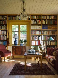 a living room filled with lots of furniture and bookshelves next to a window