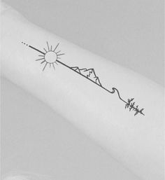 a small tattoo on the arm of a woman with mountains and sun in the background