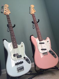 two electric guitars sitting side by side in a room