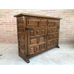 a large wooden cabinet sitting on top of a white floor next to a brick wall