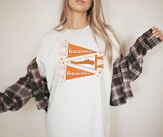 Our Tennessee Pennant Graphic Tee is the perfect everyday shirt to throw on! The coziest shirt to show off your Tennessee pride! Screen printed design on the t-shirt color of your choice. S I Z I N G: Small Medium Large XL 2XL These shirts are Comfort Colors and are unisex cut. They are soft and comfy. - For a standard fit, we recommend choosing your normal size. - For a fitted fit, we recommend sizing down. - For an oversized fit, we recommend sizing up. F A B R I C A T I O N: - Our shirts are White Long Sleeve School Spirit Shirt, White Long Sleeve Shirt For School Spirit, Trendy Cotton Shirt For College, White Cotton School Spirit Shirt, White Cotton Shirt With School Spirit, White Cotton Shirt With School Spirit Style, White Cotton Shirt For School Spirit, Tennessee Graphic, Cowboy Shirt