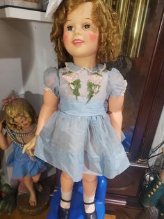 an old doll is sitting on top of a blue stool in front of a mirror