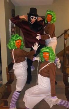 four people dressed in costumes and wigs are dancing on the stairs with their hands together