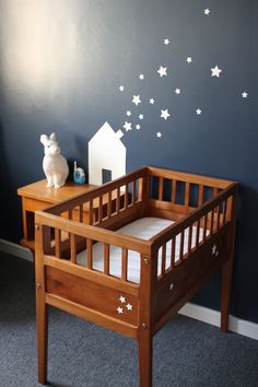 a baby crib with stars painted on the wall above it and a small white dog statue