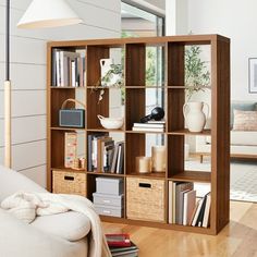 a living room filled with furniture and bookshelves next to a white couch on top of a hard wood floor