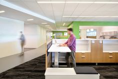 there is a man that is standing at the desk in an office building with green walls