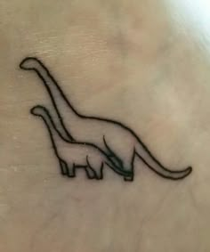 a small dinosaur tattoo on the back of a woman's left arm