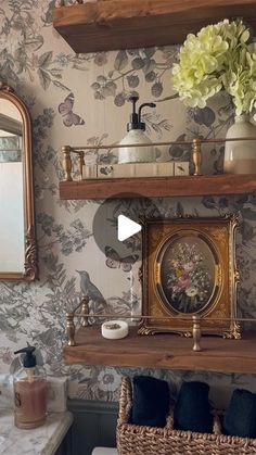 a bathroom with floral wallpaper and wooden shelves above the sink, along with two mirrors