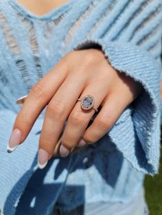 a woman's hand with a ring on her finger and a blue sweater in the background