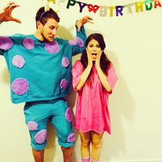 a man and woman dressed in costumes standing next to each other with their hands up