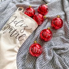 red christmas ornaments sitting on top of a blanket next to a bag with merry written on it