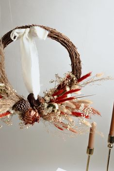 a wreath with feathers and other decorations hanging from it's side, on a table