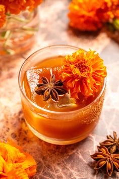 an orange drink with flowers in it on a table