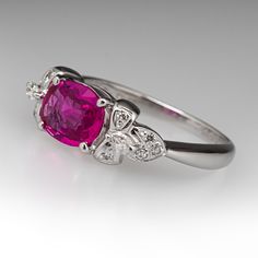 a close up view of a ring with a pink stone and two diamonds on it