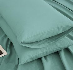 a close up of a bed with two pillows and a book on the pillowcase