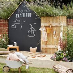 a blackboard with writing on it in the middle of some grass and wooden furniture