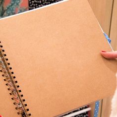 a person holding a notebook in their right hand and writing on it with a blue pen