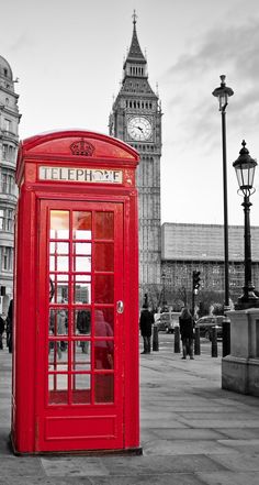 a red phone booth sitting in front of the big ben clock tower