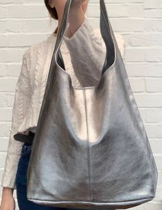 BACK IN STOCK! A simply stunning & stylish, metallic leather slouch bag with matching purse. ABOUT THE BAG.. 4 stunning colours available. Open top with magnetic dot closure. Additional zipped purse attached via a chain.  Silver metal hardware.   Handle drop: 38cm. Dimensions: H60cm x W37cm x D16cm  Handmade in Italy  All orders are dispatched within 1-3 working days from the UK via Royal Mail. Leather Slouch Bag, Personalized Family Print, Family Pet Portraits, Slouch Bag, Purse Outfit, Slouchy Bag, Slouch Bags, Unusual Gift, Bag Silver