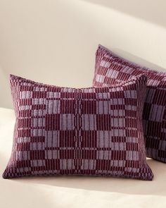 two red and white pillows sitting on top of a bed