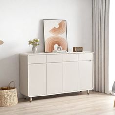 a white cabinet sitting next to a window in a room with wooden floors and curtains