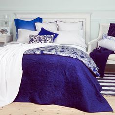 a bedroom with blue and white bedding, pillows and blankets on the bedspread