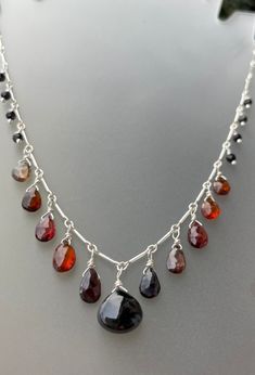 Beautiful black spinel gemstones line a sterling silver bar and chain necklace, the pendant is also black spinel, a smooth aaa luxe gemstone. The necklace is lined with gorgeous sapphire briolettes in orange and brown tones. 19 1/2 inches long. Shaped and hammered sterling hook clasp embellished with tiny black spinel gems. Spinel Jewelry Necklace, Silver Long Drop Gemstone Necklaces, Silver Gemstone Long Drop Necklaces, Black Sterling Silver Long Drop Jewelry, Modern Black Jewelry With Sterling Silver Clasp, Silver Gemstone Necklaces, Black Sterling Silver Single Strand Jewelry, Black Sterling Silver Jewelry With Lobster Clasp, Black Necklace With Sterling Silver Clasp