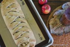 a loaf of bread sitting on top of a pan next to an apple and cinnamon roll