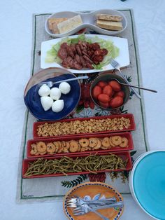 an assortment of food is laid out on a table with utensils and plates