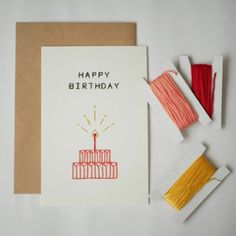 a birthday card with thread and spools of thread on the table next to it