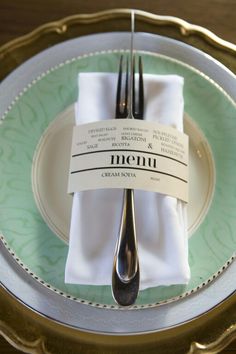 a place setting with silverware and napkins on a gold rimmed table cloth