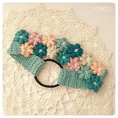 there is a crocheted headband with flowers on it and a black ring