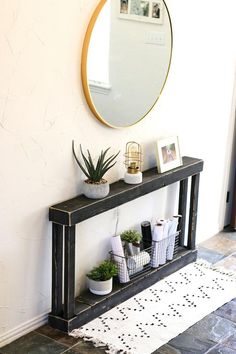 an entryway with a mirror and plants on the side table in front of it