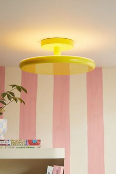 a yellow light hanging from the ceiling in a room with pink and white striped walls