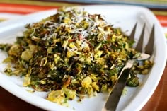 a white plate topped with lots of veggies next to a knife and fork